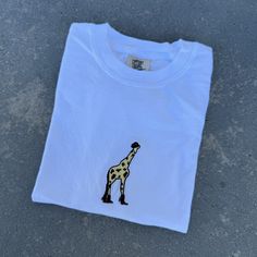 Introducing our embroidered Giraffe Cowboy Comfort Colors T-shirt, perfect for making a bold statement. Crafted with quality and comfort, this t-shirt guarantees an unparalleled experience of luxury. Made from 100% ring spun cotton. Elevate your wardrobe with this flawless blend of style and comfort, and indulge in the softness and exceptional quality it offers. Shop now and discover the perfect combination of comfort and style for your wardrobe. Please take note that if you desire an oversized Embroidered Giraffe, Giraffe Shirt, T-shirt Broderie, 30 And Single, Embroidered Tshirt, Shirt Price, Tshirt Colors, Comfort Colors, Spun Cotton