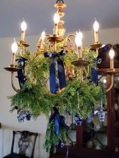 a chandelier is adorned with greenery and blue ribbon