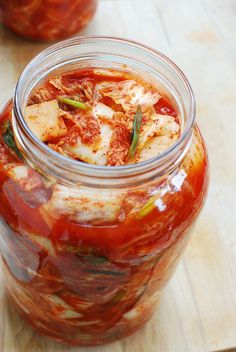 two jars filled with food sitting on top of a wooden table