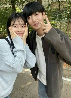 two people posing for a photo with one holding his hand up to the other's face