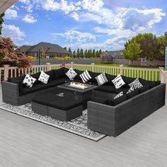 an outdoor living room with black couches and white pillows