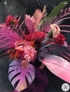 a vase filled with lots of colorful flowers and greenery on top of a table