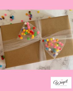 a gift wrapped in brown paper with colorful candies on it