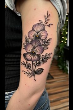 a woman's arm with flowers and leaves on it