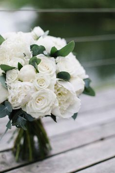 a bouquet of white flowers sitting on top of a wooden table