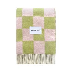 a green and pink checkered blanket with a label that says maison dux on it