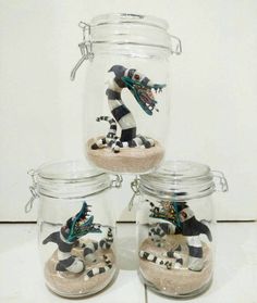 three glass jars filled with sand and small figurines