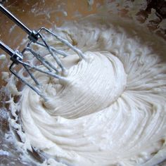 a mixing bowl filled with white batter and whisk attachments for making cake