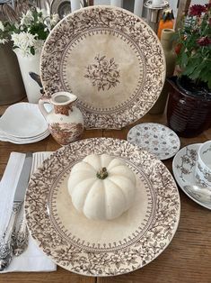 there are plates with pumpkins on them and flowers in vases next to each other