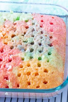 a colorful cake in a glass dish on a cooling rack