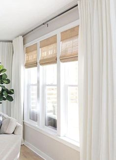 a living room with white drapes and curtains on the windowsills, along with a potted plant