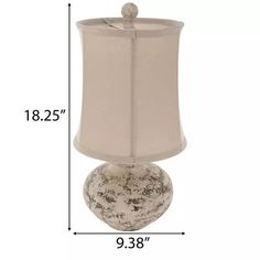 a white lamp with a beige shade on it's side and measurements for the base