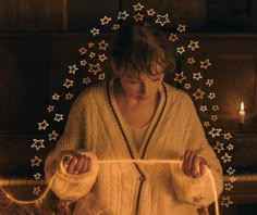 a woman standing in front of a fireplace holding a string with stars all over it