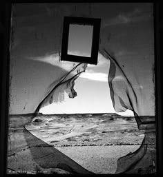 a black and white photo of the ocean with a square frame hanging from it's ceiling