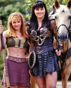 two women in costumes standing next to a horse