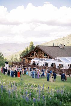 a group of people standing in front of a wooden building with white drapes on it