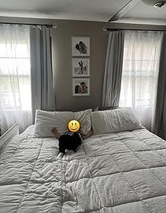 a person laying on top of a bed with a smiley face ball in front of them