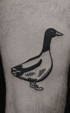 a black and white duck tattoo on the back of a man's leg,