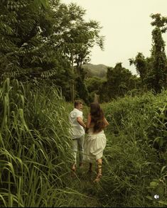 a man and woman walking through tall grass