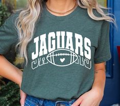 a woman wearing a green shirt with the word jaguars on it and a football