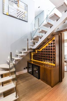 there is a wine rack on the wall under the stairs in this room with wooden flooring