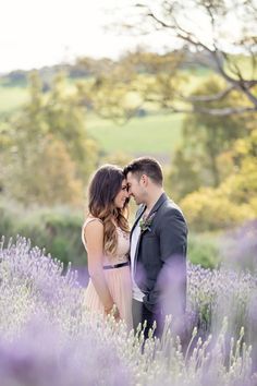 a man and woman standing next to each other in a lavender field