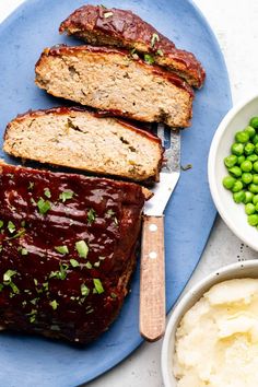 sliced meatloaf on a blue plate with mashed potatoes and peas