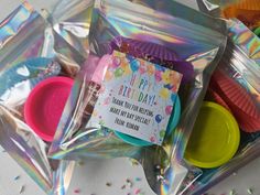 a bag filled with lots of different colored plastic cups next to confetti and sprinkles