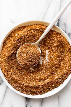 a white bowl filled with spices and a spoon