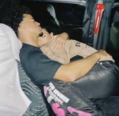 a man laying in the back of a car with his head on someone's chest