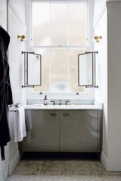 a bathroom with a sink, mirror and towels hanging on the rack in front of it