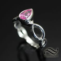 a close up view of a ring with a pink stone in it's center