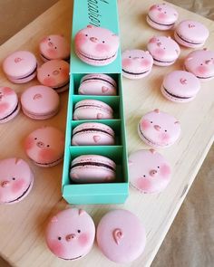 some pink macaroons are in a blue box on a table with other macaroons