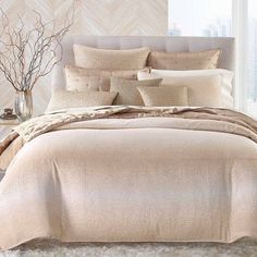 a bed with beige comforters and pillows