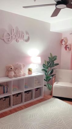 a pink and white room with teddy bears, bookshelves and a ceiling fan