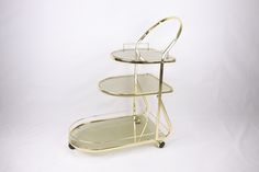 a three - tiered serving cart with glass shelves on the bottom and wheels, against a white background