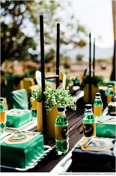 the table is set up with green and yellow bottles, napkins, and place settings