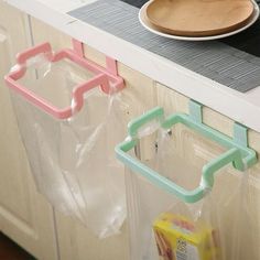 two plastic bags are hanging on the kitchen counter next to a wooden plate and bowl