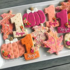 decorated cookies in the shape of autumn leaves and pumpkins are displayed on a tray