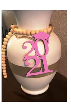 a white vase sitting on top of a table with a pink number 21 sign attached to it