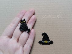 a hand holding a small black beaded witch hat