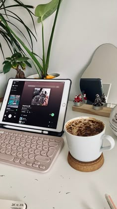 a laptop computer sitting on top of a white desk next to a cup of coffee