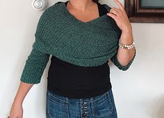 a woman standing in front of a mirror making the peace sign with her hand while wearing a green sweater and jeans