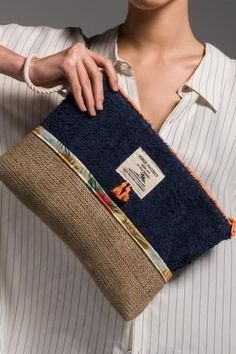 a woman is holding a blue and tan purse with an orange stripe shirt on it