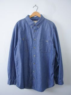 One vintage 1990's blue button up denim shirt, men's size large * Pointed collar with buttons. * 8 button closures down the center. * 2 buttons on each wrist cuff, and 1 button on each sleeve. * 2 chest pocket. * Tall fit. * Color scheme: denim blue. | CONDITION | A+. Gently used vintage item. | BRAND | Scandia Woods. Made in India. | SIZE | Marked as a men's Large Tall (USA). PLEASE compare the measurements below to a similar item that fits you for the best sizing! ~ Garment laying flat. Double Summer Shirts Men, Chambray Denim Shirt, Oversized Denim Shirt, Chambray Fabric, Floral Shirt, Denim Blue, Summer Shirts, Denim Shirt, Etsy Vintage