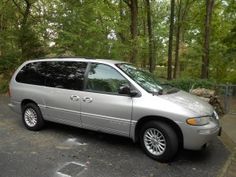 a silver van parked in a parking lot next to trees