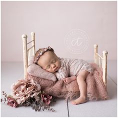 a baby sleeping on top of a pink blanket in a chair with flowers around it