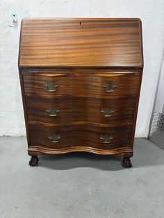 an old wooden chest of drawers with brass hardware on the top and bottom, against a white wall