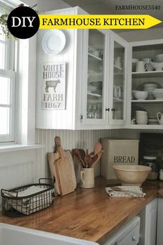 a wooden counter top in a kitchen next to white cupboards and dishes on shelves