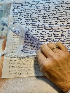 an old woman's hand is writing on paper